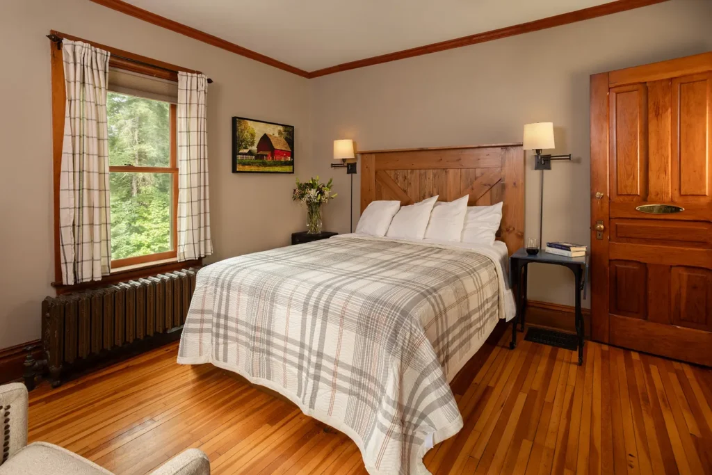 Salmo Room: bed with plaid quilt beside a sunny window