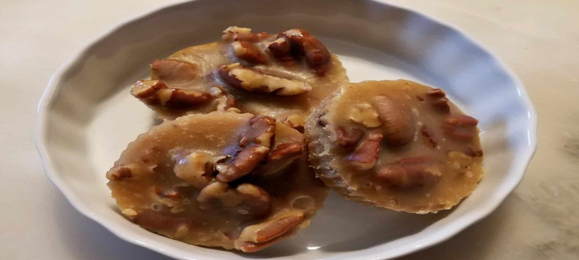 Three round pralines in white dish with scalloped edges