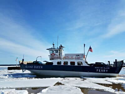 Madeline Island Ferry on snow and ice covered water carrying trucks and cars